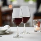 „Ribier borospoharak elegáns éttermi terítéken, vörösborral töltve, gyertyafényes fine dining hangulatban.”