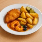 Polikarbonát, törhetetlen 25 cm-es fehér lapostányéron rántott csirke sült burgonyával és savanyúsággal, gusztusos catering tálalásban, természetes fényű éttermi környezetben.