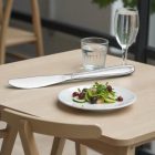 „EURO Evokes ECO rozsdamentes evőkés modern bisztróasztalon, salátával és szénsavas vízzel, nappali fényben.”