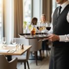 felszolgáló nagy tálcával több itallal éttermi környezetben