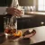 High-quality product lifestyle photography. A professional copper Julep bar strainer from image_baf12a.png with a glossy metallic finish is resting next to a heavy crystal mixing glass and a matching 