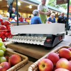 Tolósúlyos konyhamérleg friss gyümölcsökkel, piaci környezetben