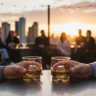 LAV Adora whiskys poharak jéggel egy modern tetőtéri bár asztalán naplementekor