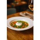 Boj fehér porcelán 23 cm-es leveses mélytányér színes zöldségleves tálalásával, elegáns éttermi környezetben, teljes tányérszéllel látható fine dining hangulatban.