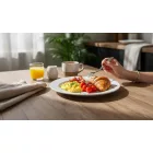 Boj fehér porcelán 23 cm-es menüs tányéron töltött csirkemell zöldbabbal, sült burgonyával és mártással, elegáns fine dining éttermi tálalásban, borospohárral a háttérben.
