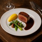 Boj fehér porcelán 20 cm-es desszertes tányér elegáns fine dining tálalásban, modern éttermi környezetben, ízlésesen tálalt étellel és letisztult asztali hangulattal.