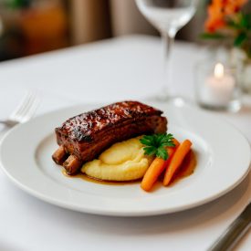 Italia 24 cm-es fehér porcelán lapostányéron omlós sült sertésoldalas burgonyapürével és párolt répával,